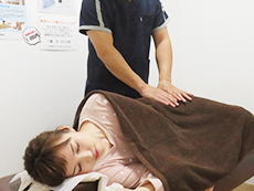 横向きに寝る患者さんの腰を優しく施術